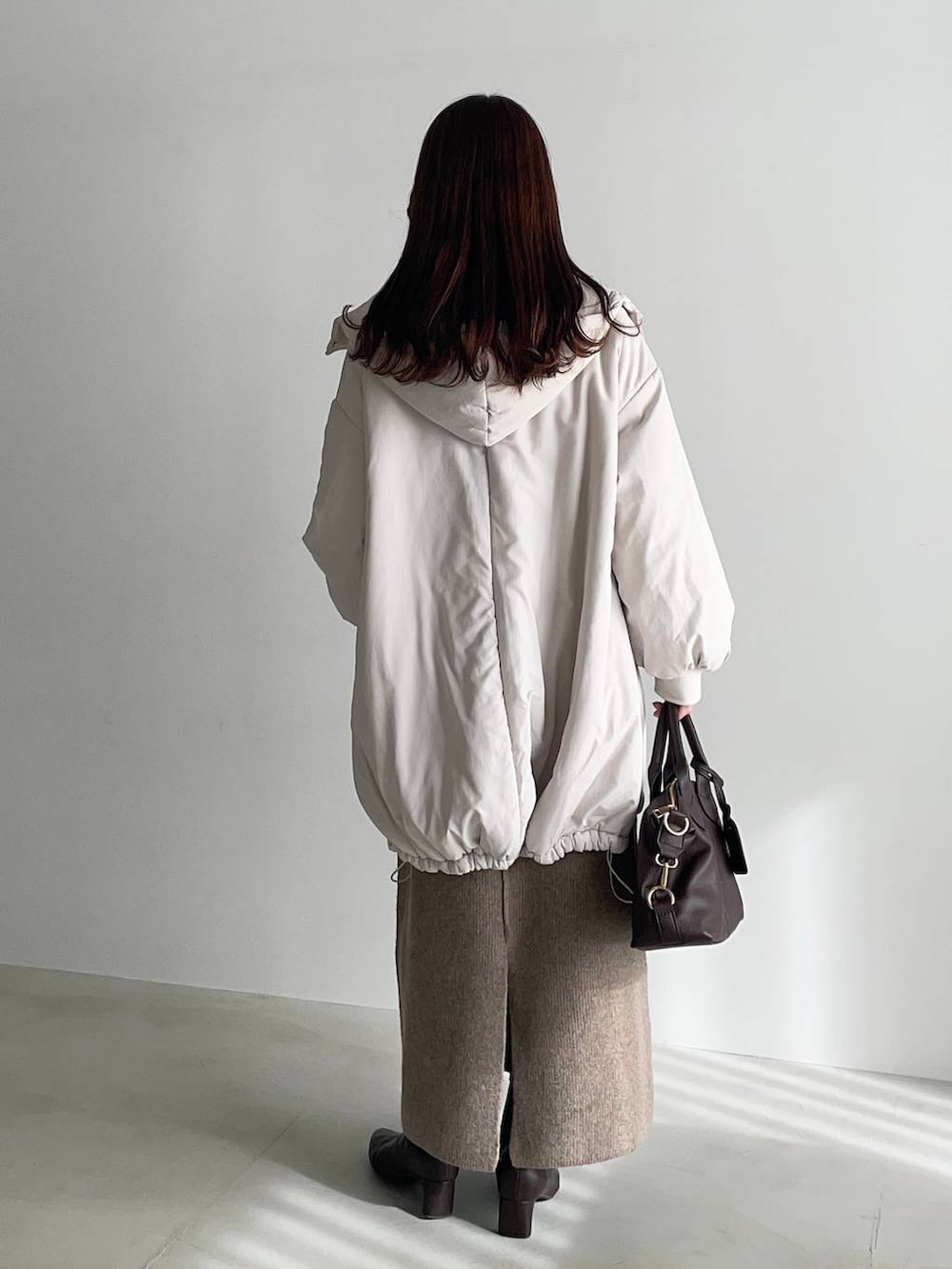 ブラウン系のボストンバッグ、ブラウン系のブーツ、ベージュ系のワンピースを着用したレディースの冬コーディネートの2枚目の写真