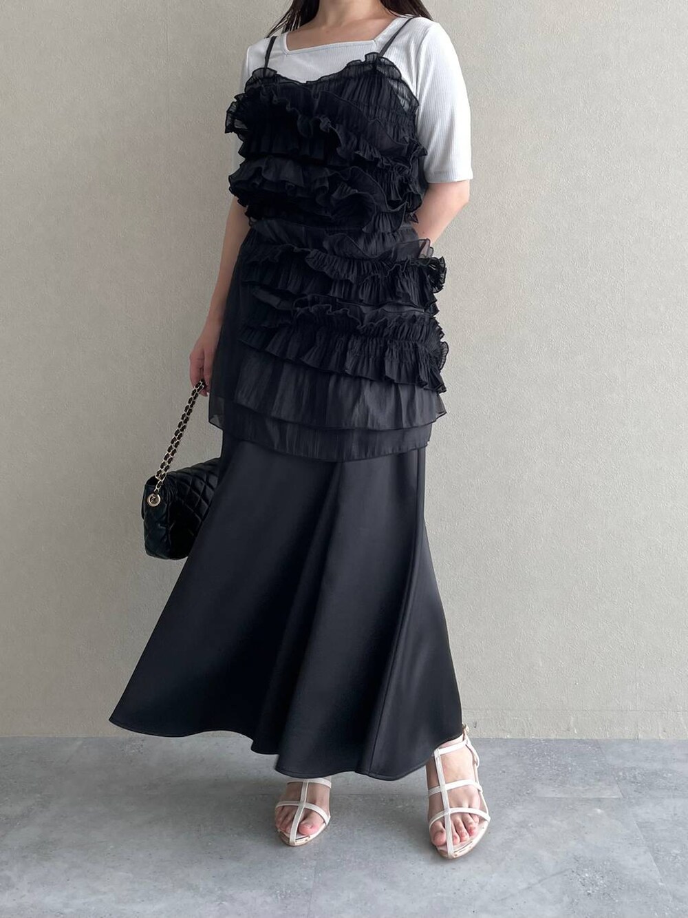 ブラック系のスカート、ブラック系のショルダーバッグ、ホワイト系のサンダルを着用したレディースの夏コーディネートの4枚目の写真