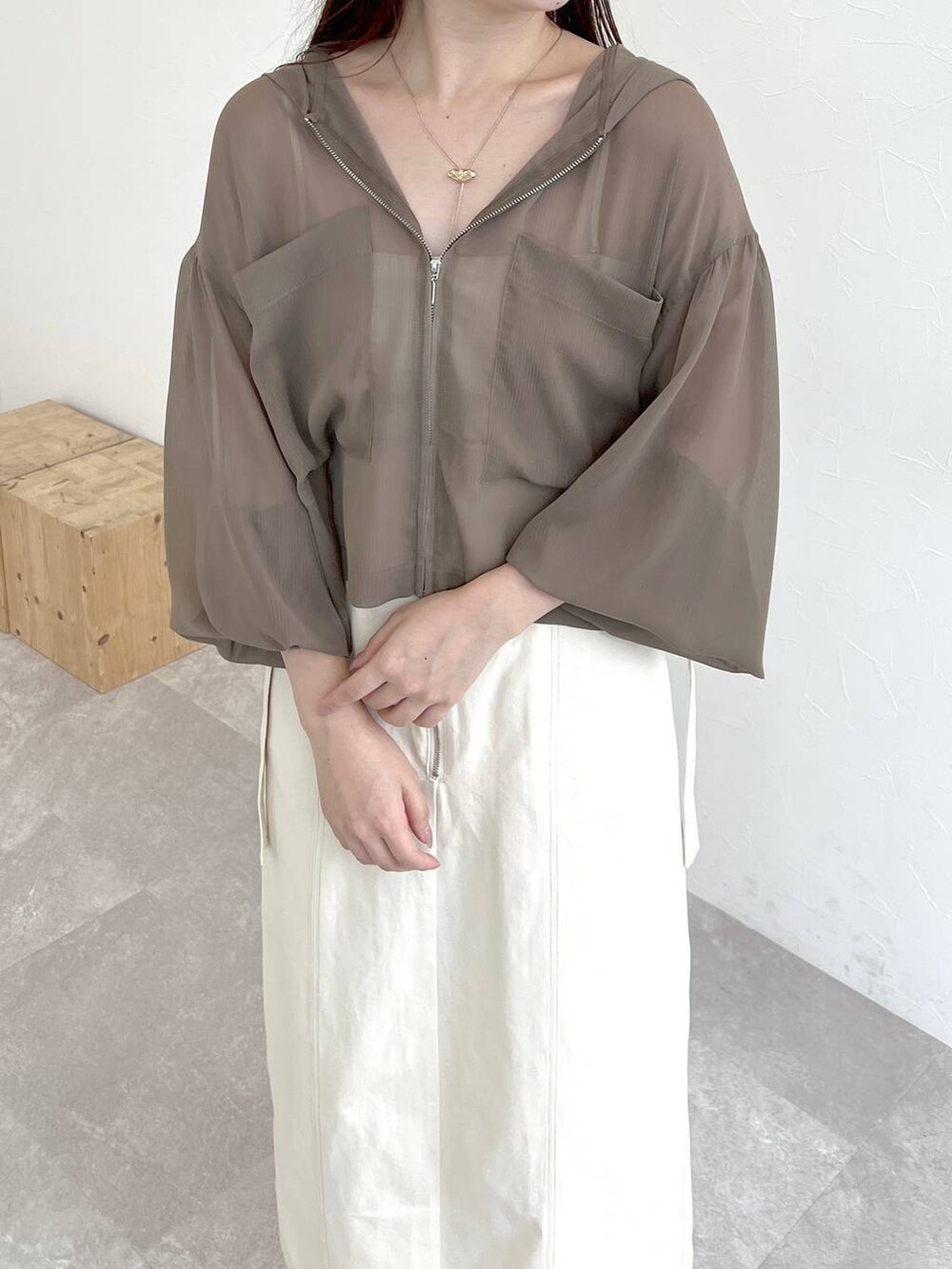 ホワイト系のスカート、ブラウン系のパーカー、ホワイト系のショルダーバッグを着用したレディースの夏コーディネートの3枚目の写真