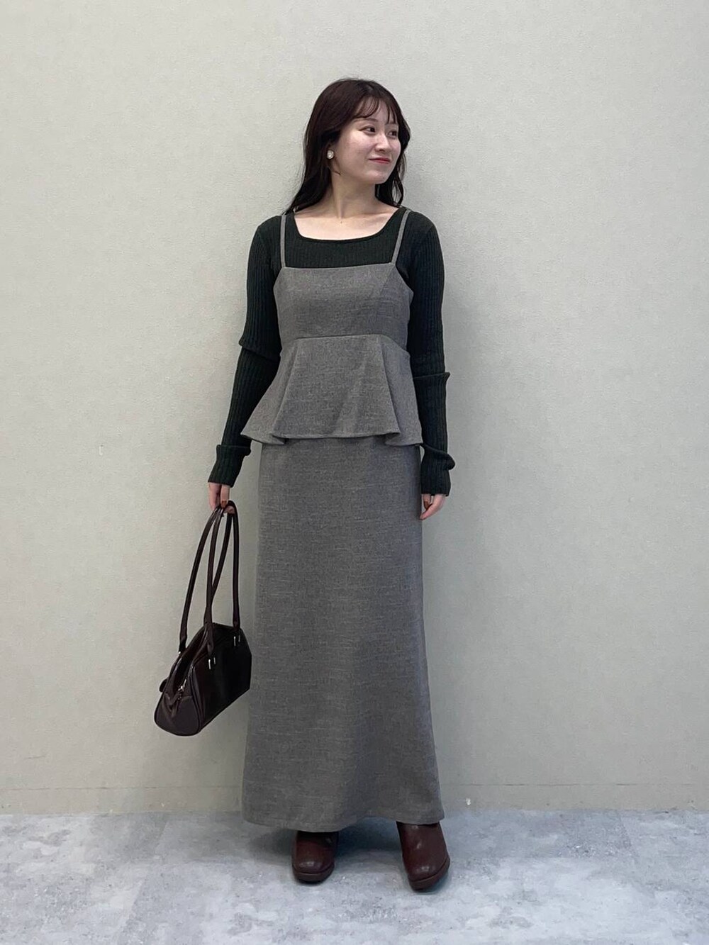 ベージュ系のピーコート、ブラウン系のブーツ、グレー系のワンピースを着用したレディースの秋コーディネートの3枚目の写真