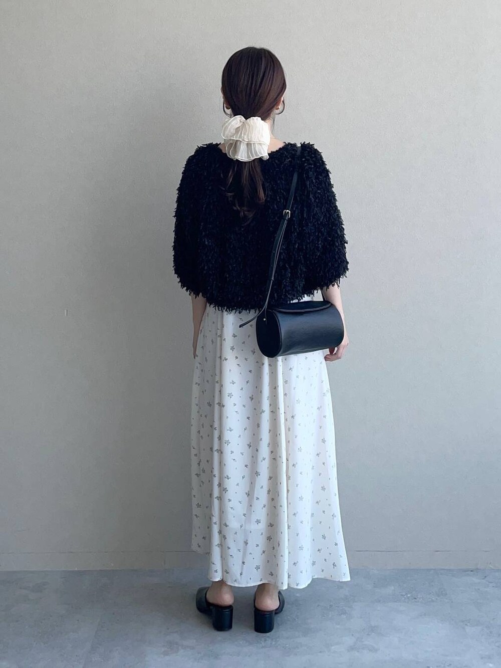 ホワイト系のワンピース、ブラック系のカーディガン/ボレロ、ブラック系のショルダーバッグを着用したレディースの夏コーディネートの2枚目の写真