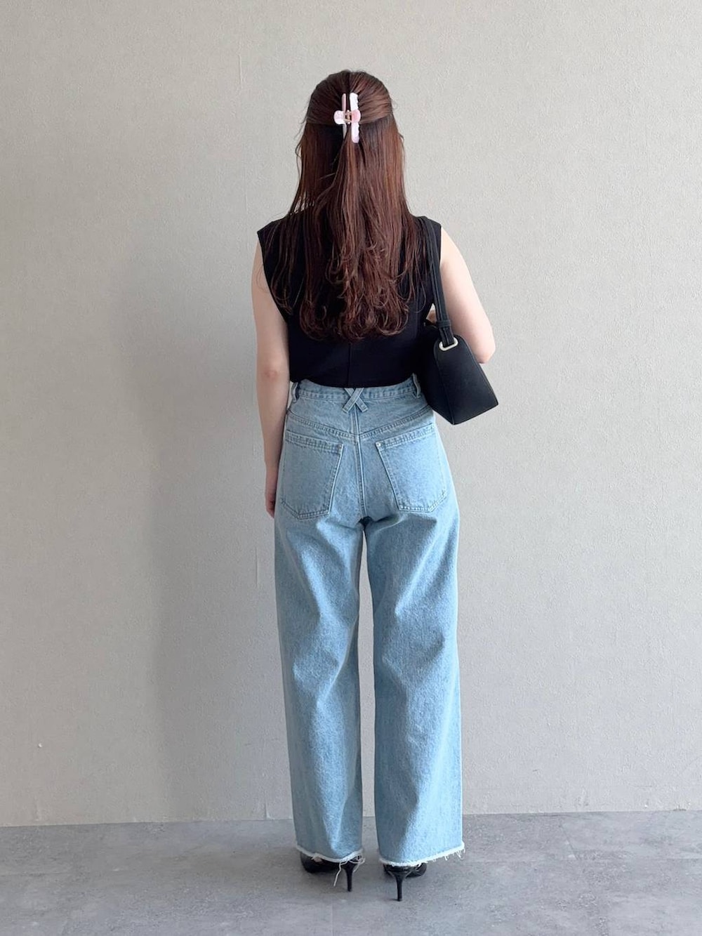 ブラック系のニット/セーター、ブルー系のデニムパンツ、ブラック系のサンダルを着用したレディースの夏コーディネートの2枚目の写真