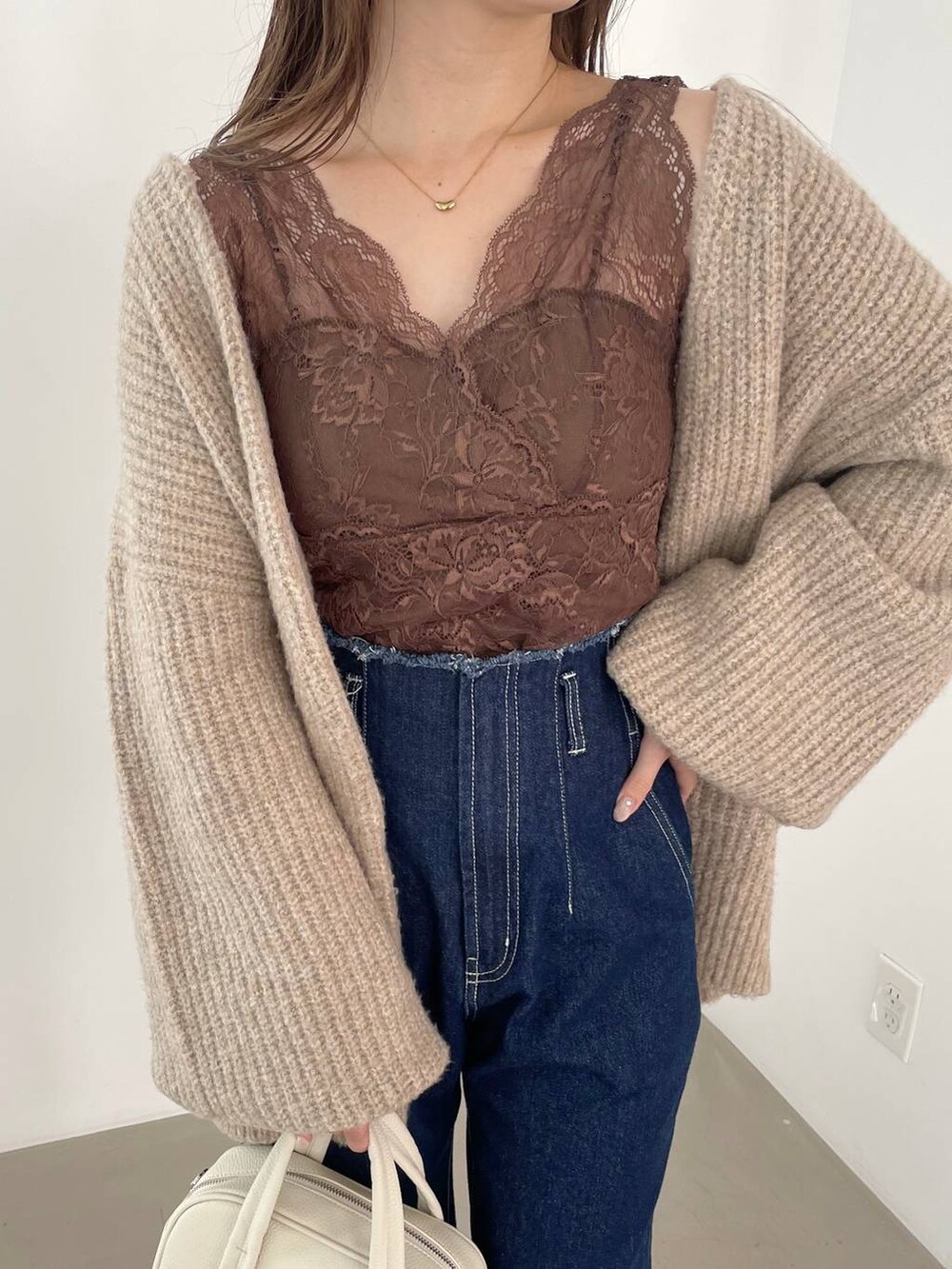 ブルー系のデニムパンツ、ホワイト系のボストンバッグ、ホワイト系のパンプスを着用したレディースの秋コーディネートの5枚目の写真