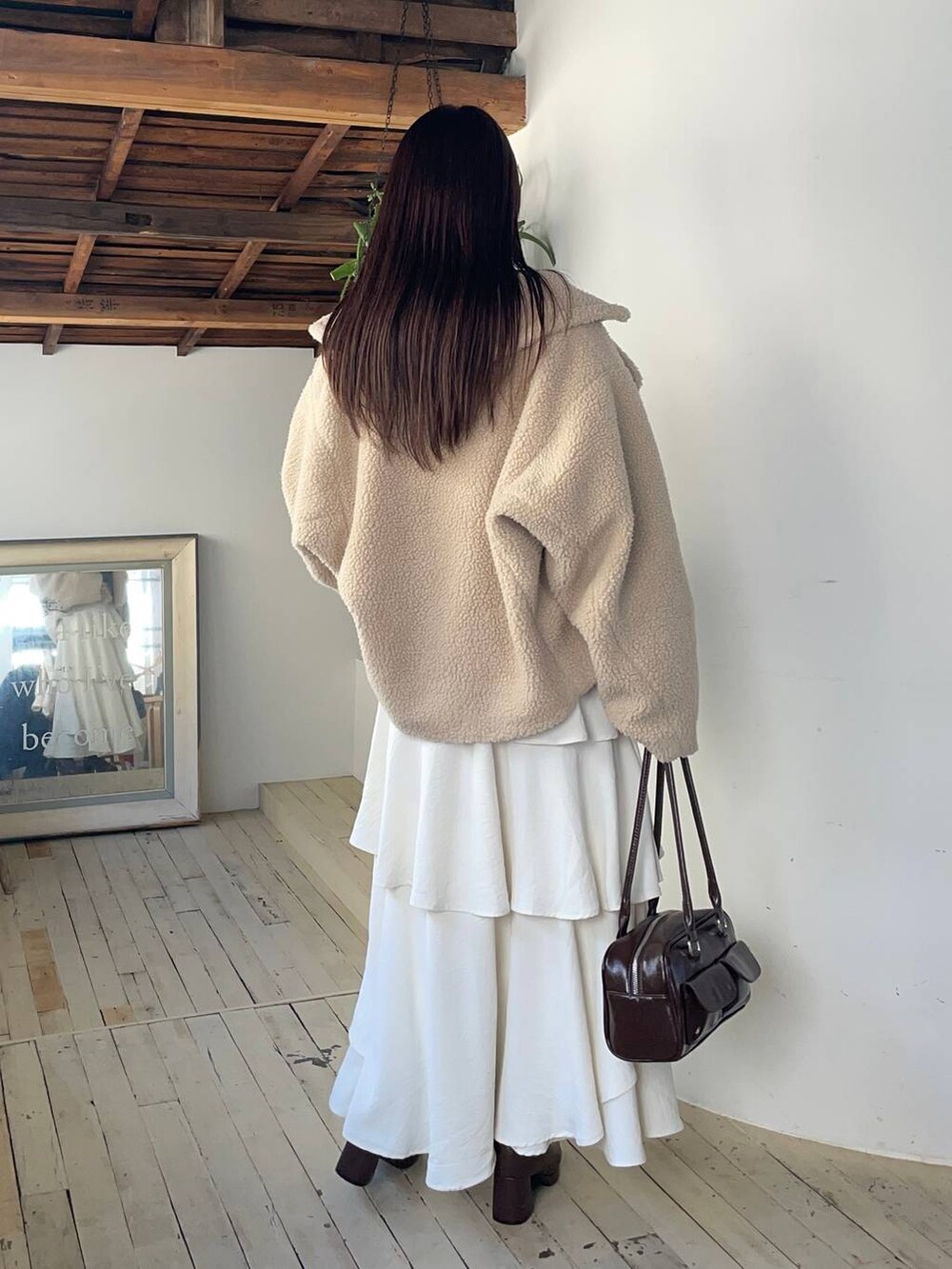 ベージュ系のピーコート、ブラウン系のブーツ、ブラウン系のニット/セーターを着用したレディースの冬コーディネートの2枚目の写真