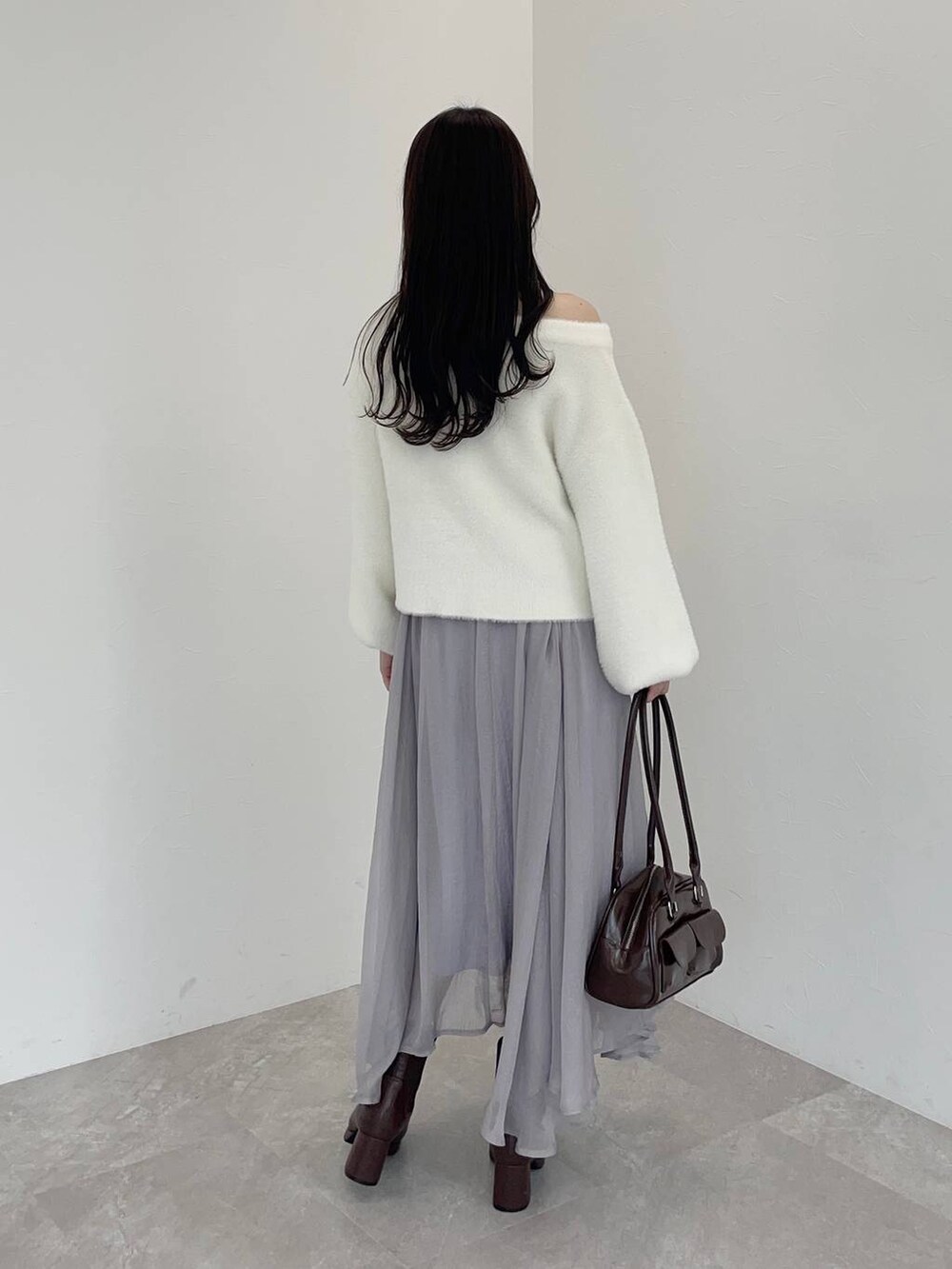 ブラウン系のブーツ、ブラウン系のハンドバッグ、ホワイト系のニット/セーターを着用したレディースの冬コーディネートの2枚目の写真