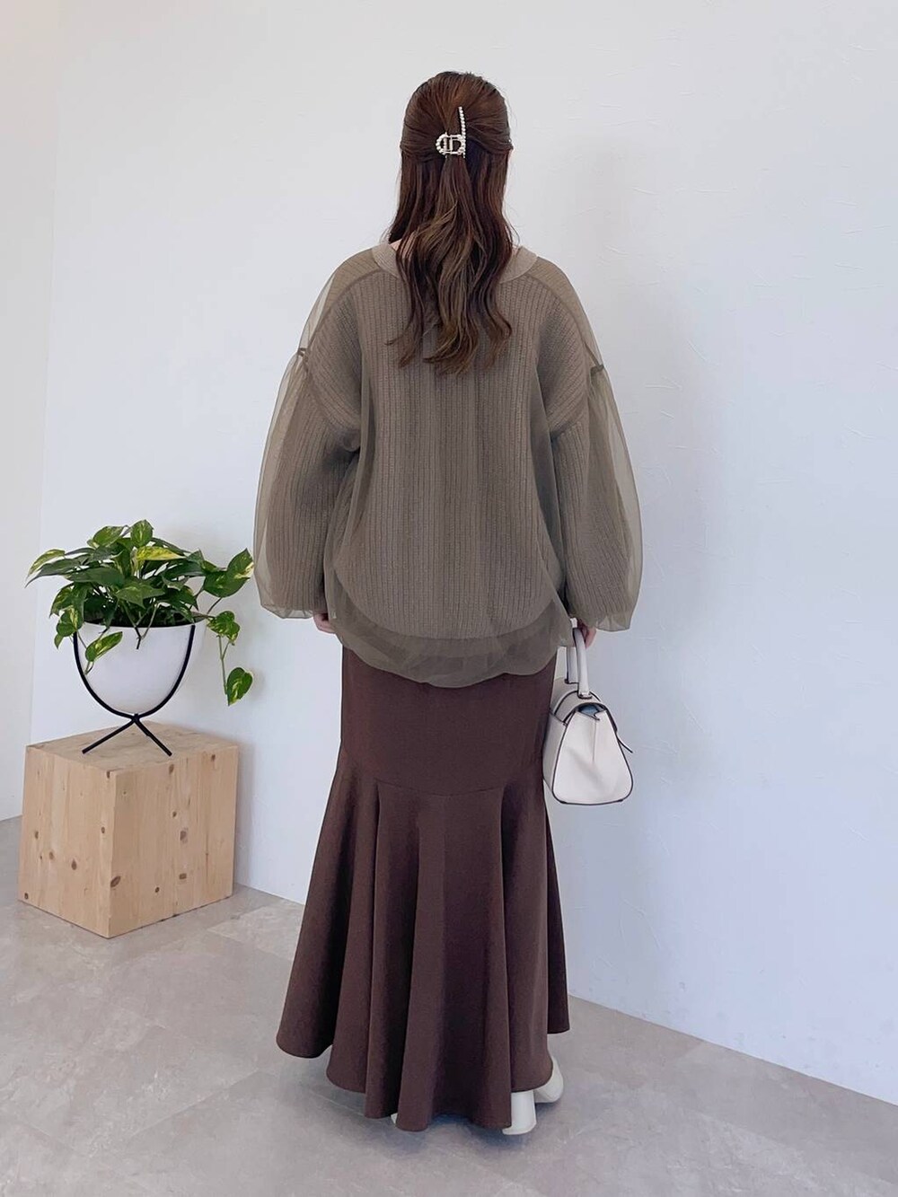 ホワイト系のハンドバッグ、ホワイト系のブーツ、ブラウン系のスカートを着用したレディースの秋コーディネートの2枚目の写真