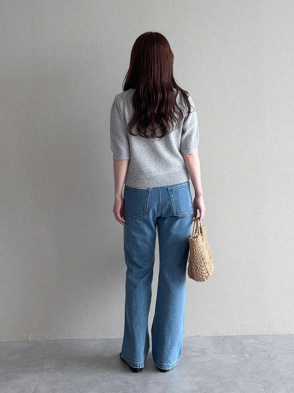 グレー系のカーディガン/ボレロ、ブルー系のデニムパンツ、ブラウン系のかごバッグを着用したレディースの夏コーディネートの2枚目の写真