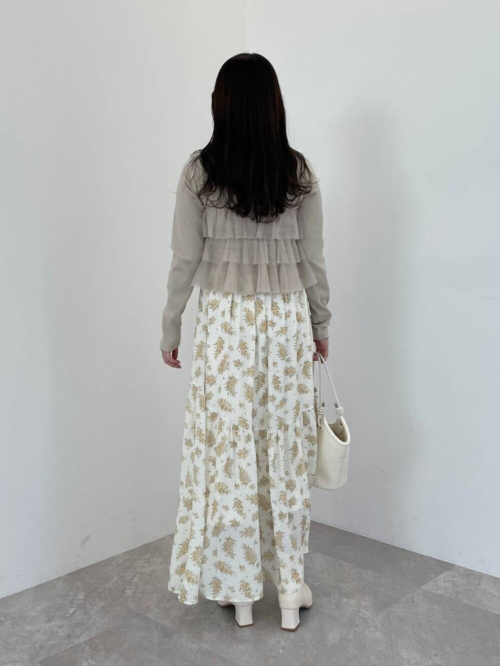 イエロー系のスカート、ベージュ系のシャツ/ブラウス、ホワイト系のブーツを着用したレディースの春コーディネートの2枚目の写真