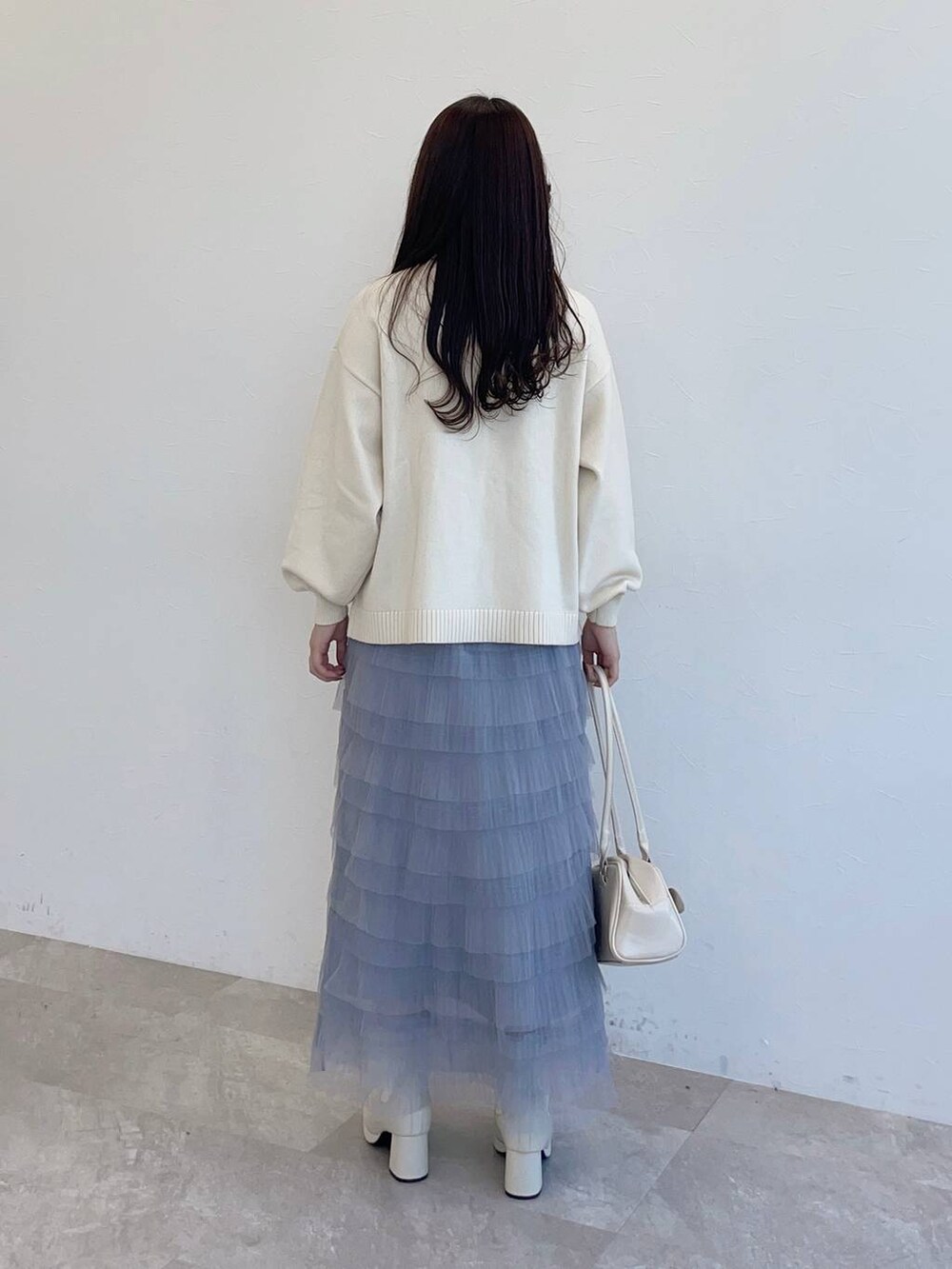 ホワイト系のブーツ、ホワイト系のハンドバッグ、グレー系のスカートを着用したレディースの秋コーディネートの2枚目の写真