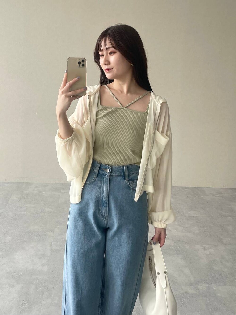 ホワイト系のパーカー、ブルー系のデニムパンツ、ブラウン系のパンプスを着用したレディースの夏コーディネートの3枚目の写真