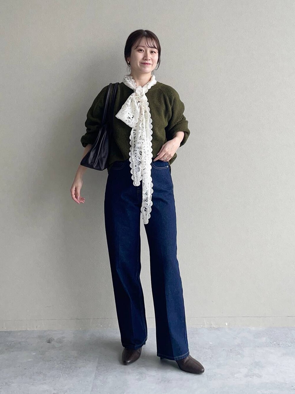 グリーン系のニット/セーター、ホワイト系のシャツ/ブラウス、ブルー系のデニムパンツを着用したレディースの秋コーディネートの2枚目の写真