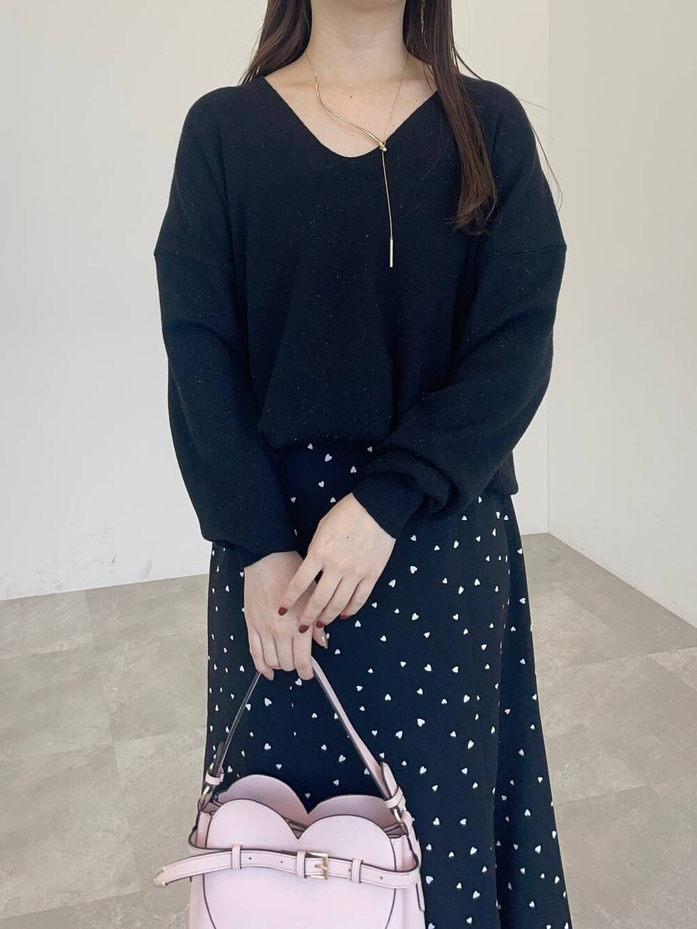 ピンク系のショルダーバッグ、ホワイト系のブーツ、ブラック系のニット/セーターを着用したレディースの冬コーディネートの3枚目の写真