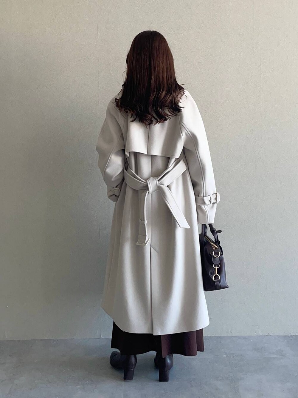 ピンク系のニット/セーター、ブラウン系のボストンバッグ、ホワイト系のチェスターコートを着用したレディースの冬コーディネートの2枚目の写真