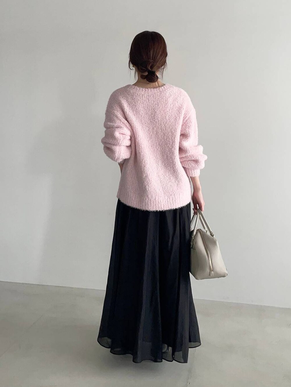 ベージュ系のハンドバッグ、ピンク系のニット/セーター、ホワイト系のサンダルを着用したレディースの冬コーディネートの2枚目の写真