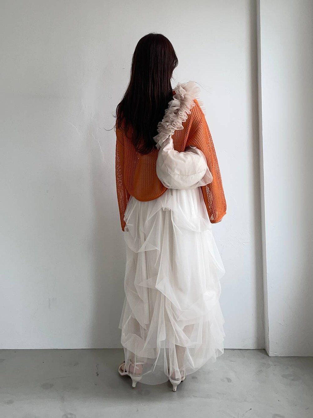 ホワイト系のスカート、オレンジ系のニット/セーター、ベージュ系のショルダーバッグを着用したレディースの夏コーディネートの2枚目の写真