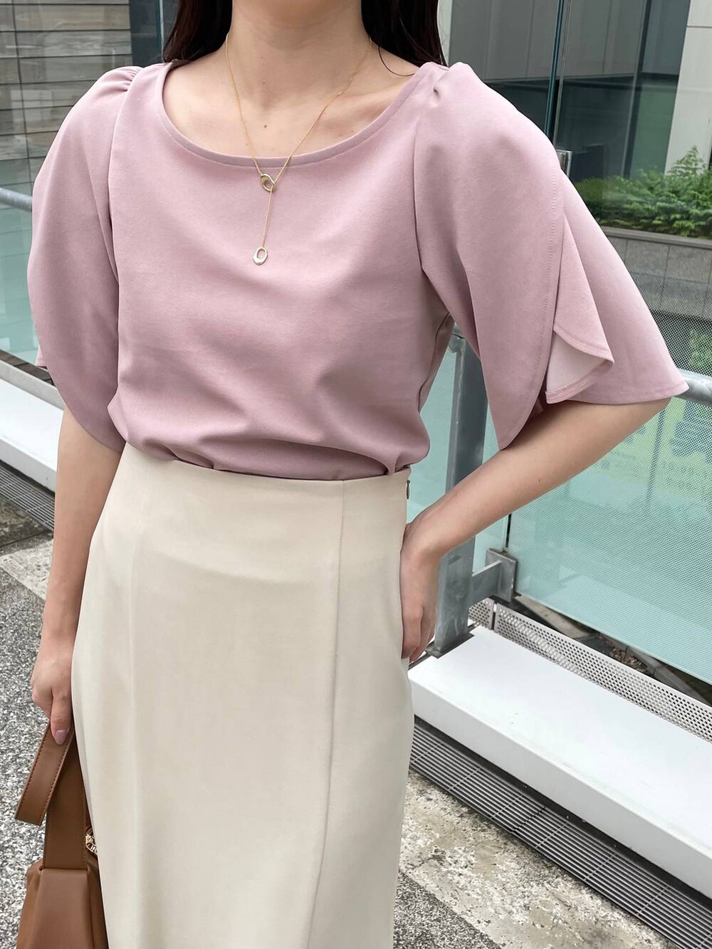 ブラウン系のショルダーバッグ、ベージュ系のスカート、ピンク系のTシャツ/カットソーを着用したレディースの夏コーディネートの3枚目の写真