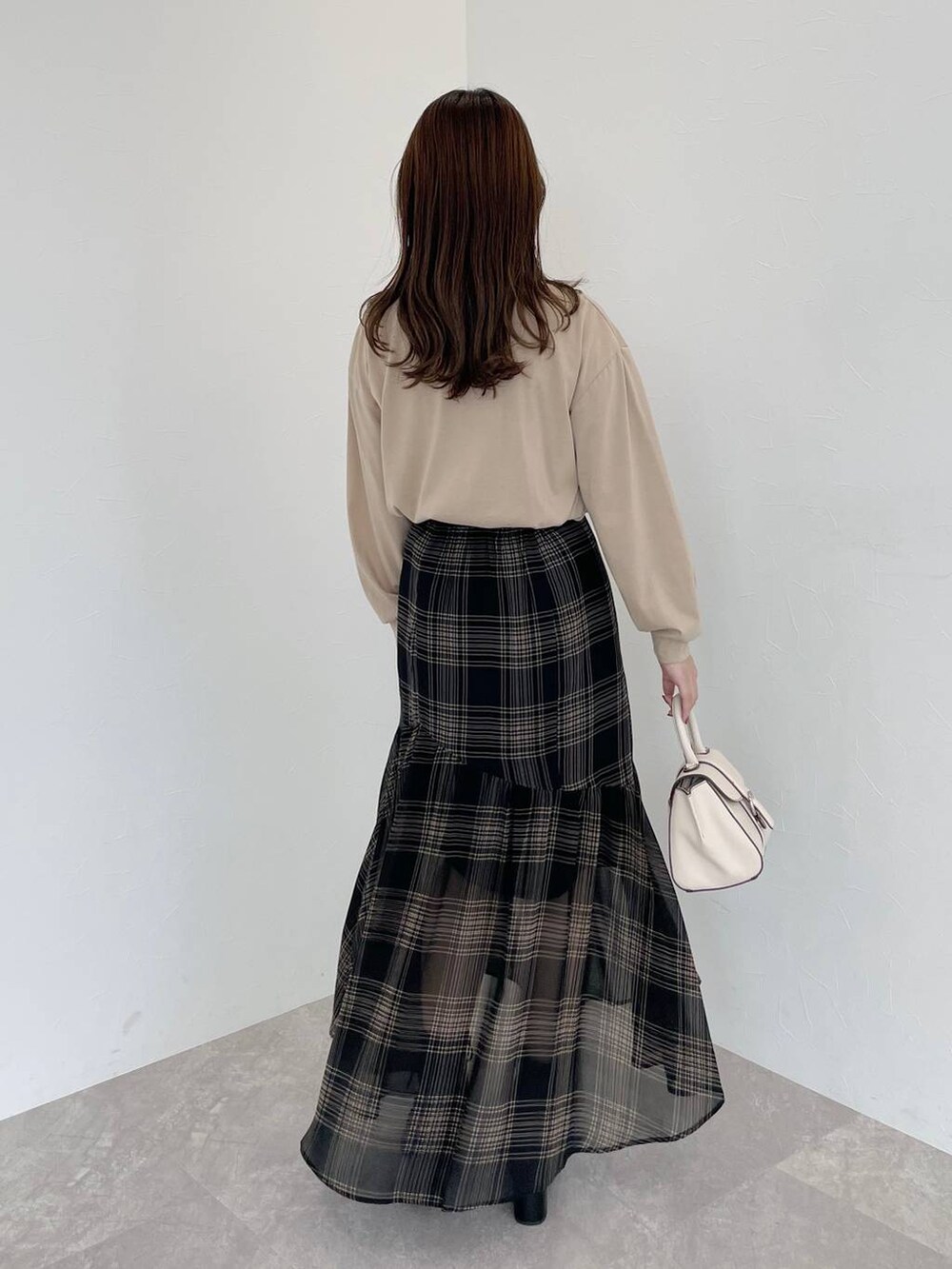 ホワイト系のカーディガン/ボレロ、ホワイト系のハンドバッグ、ブラック系のブーツを着用したレディースの秋コーディネートの5枚目の写真