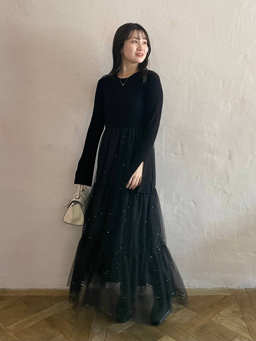 ホワイト系のハンドバッグ、ブラック系のブーツ、ブラック系のワンピースを着用したレディースの秋コーディネートの2枚目の写真