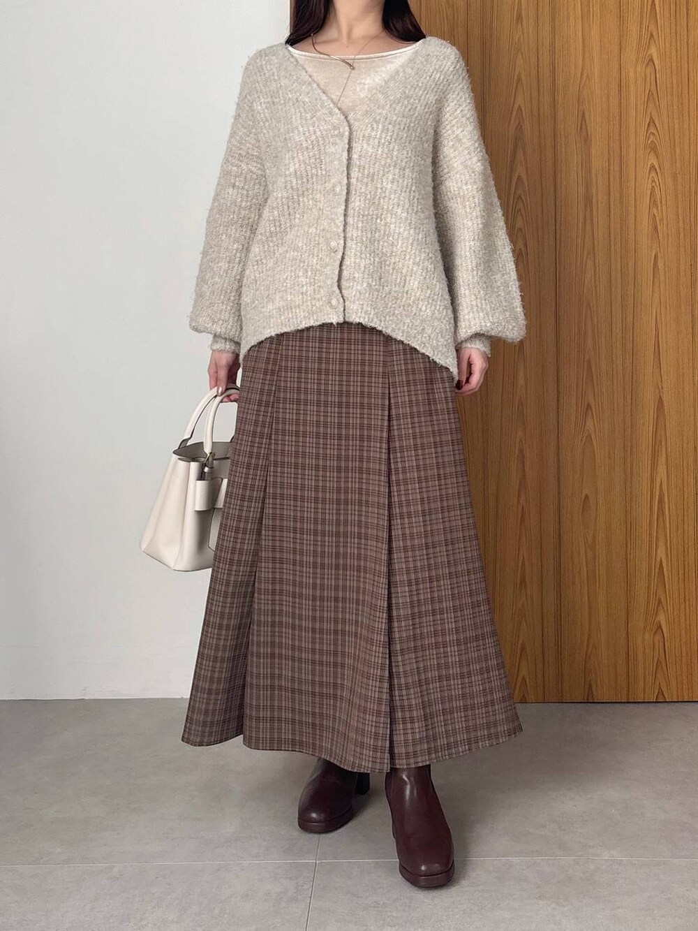 ブラウン系のブーツ、ブラウン系のスカート、ベージュ系のTシャツ/カットソーを着用したレディースの冬コーディネートの3枚目の写真