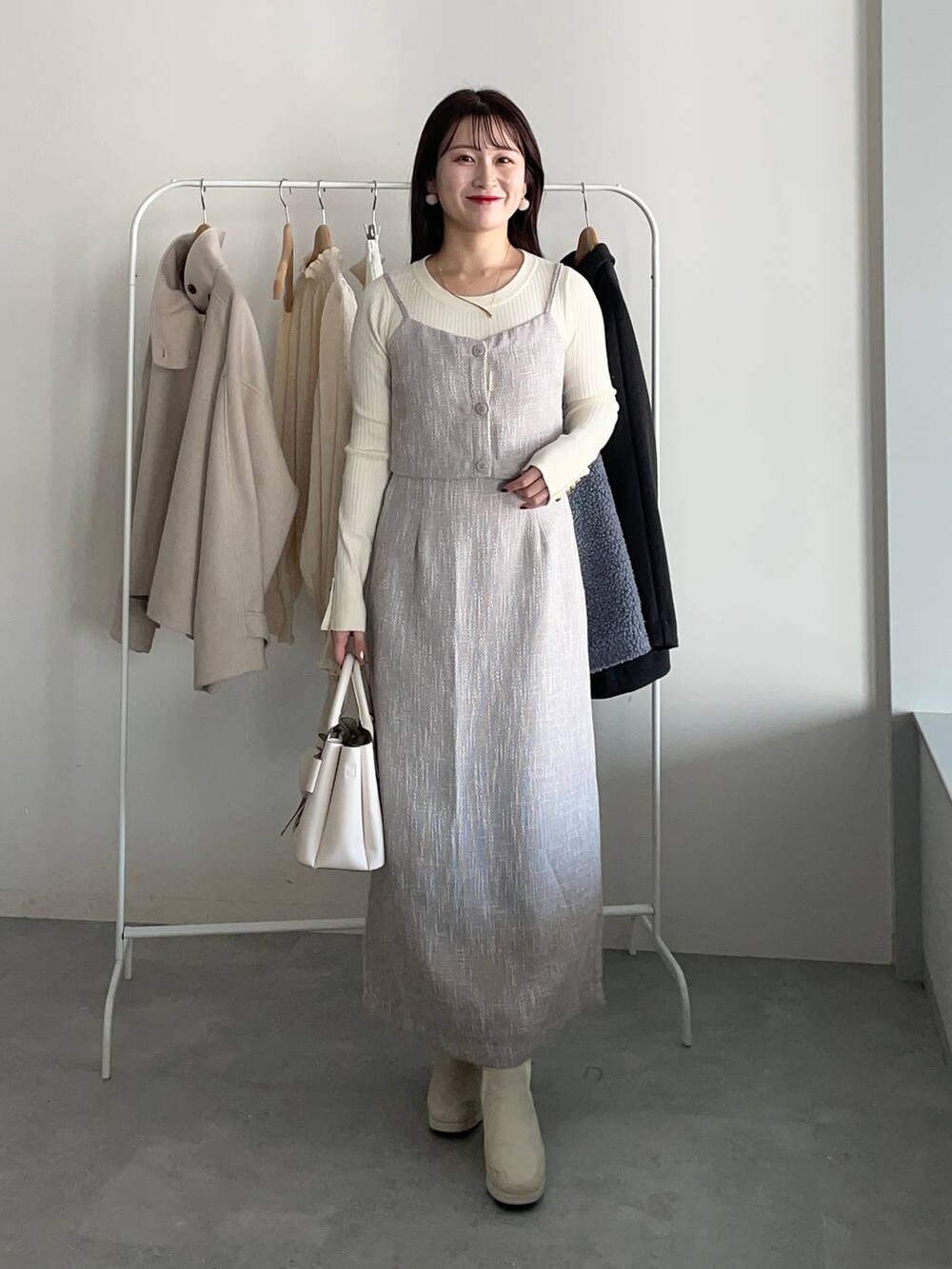 グレー系のピーコート、ホワイト系のブーツ、ホワイト系のニット/セーターを着用したレディースの冬コーディネートの3枚目の写真