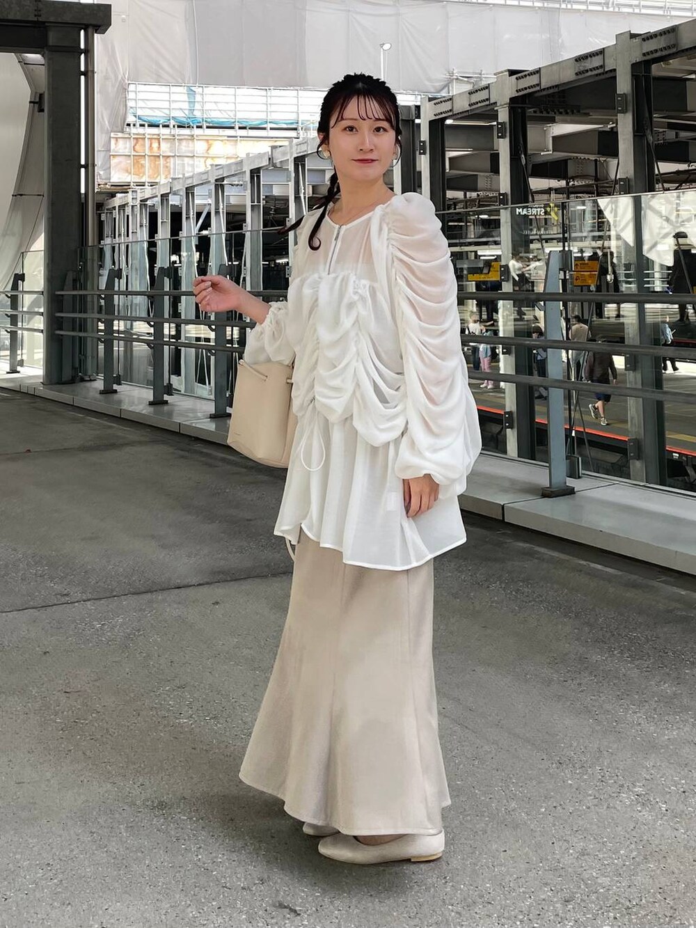 ベージュ系のスカート、ベージュ系のパンプス、ホワイト系のシュシュを着用したレディースの春コーディネートの4枚目の写真