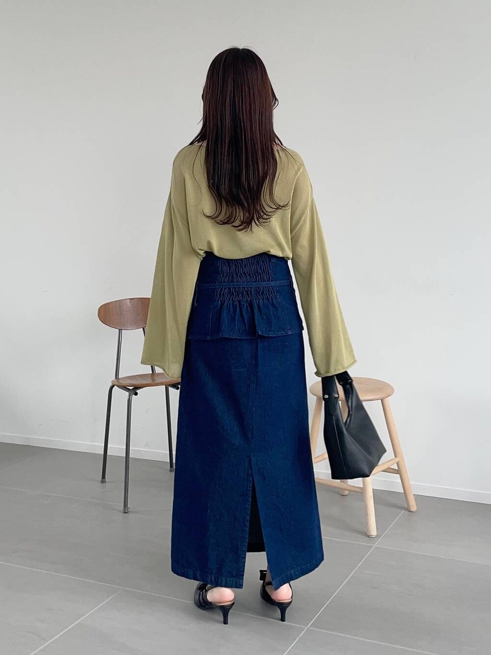 グリーン系のニット/セーター、ブルー系のスカート、ブラック系のショルダーバッグを着用したレディースの春コーディネートの2枚目の写真