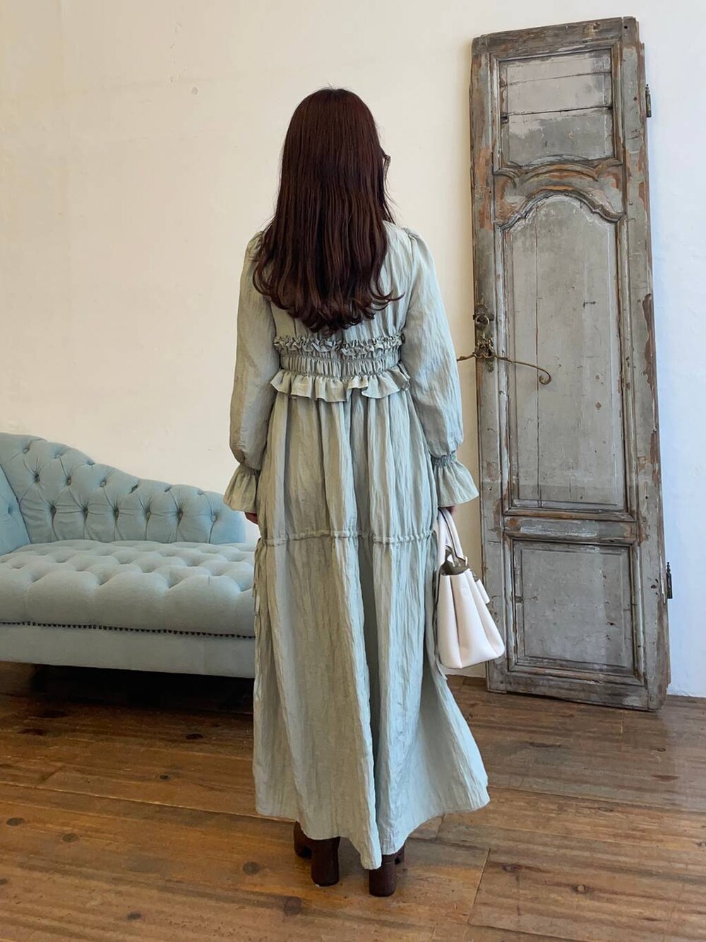 ブラウン系のブーツ、グリーン系のドレス、ホワイト系のショルダーバッグを着用したレディースの冬コーディネートの2枚目の写真