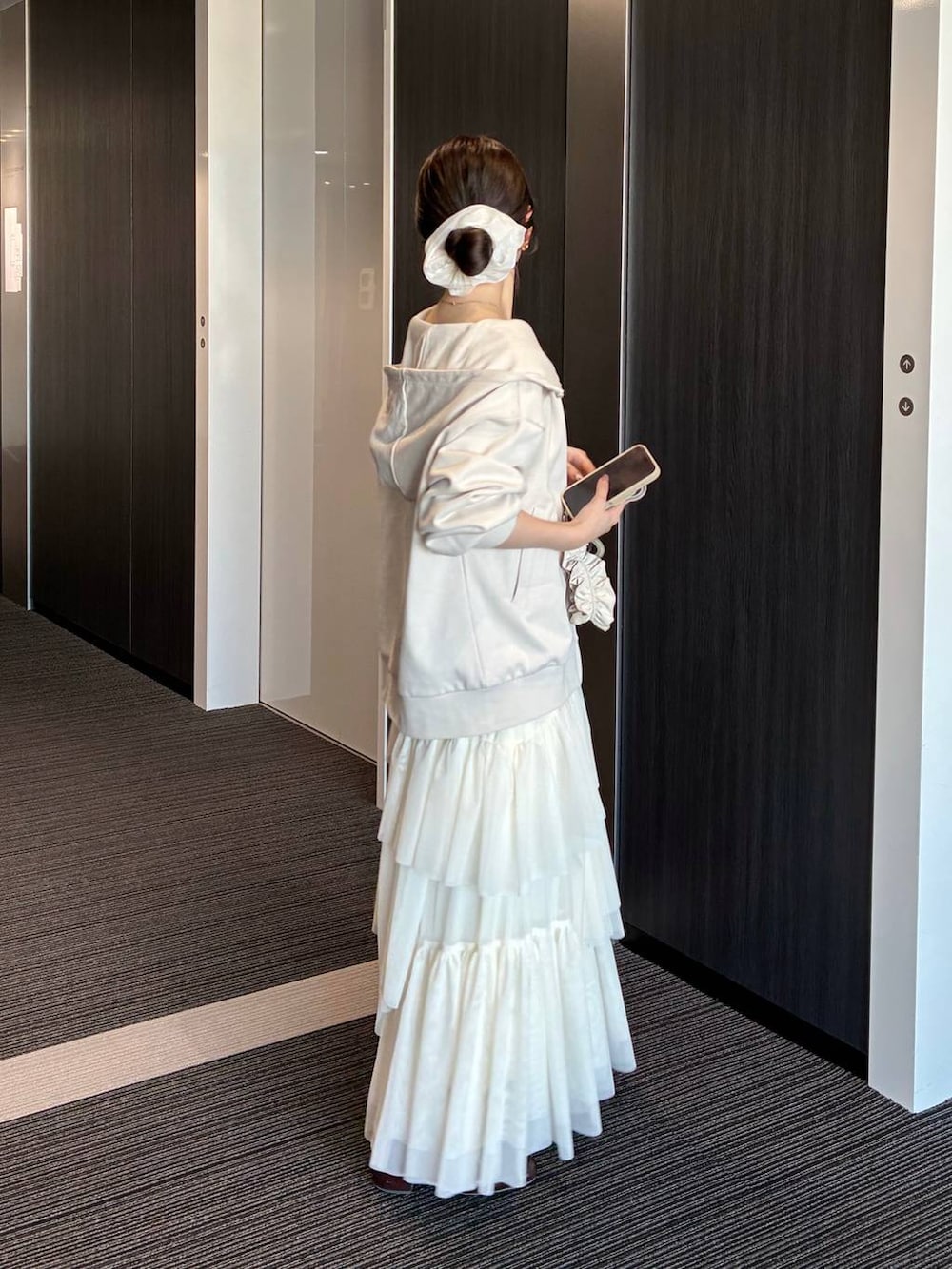 ホワイト系のパーカー、ホワイト系のスカート、ホワイト系のスマホグッズを着用したレディースの冬コーディネートの2枚目の写真