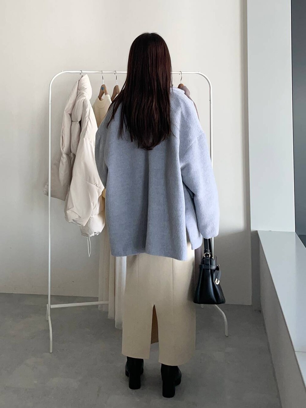 ブラック系のショルダーバッグ、ブラック系のブーツ、ホワイト系のワンピースを着用したレディースの冬コーディネートの2枚目の写真