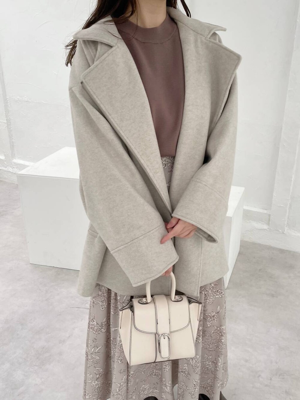 ホワイト系のハンドバッグ、ブラウン系のニット/セーター、ブラウン系のブーツを着用したレディースの秋コーディネートの3枚目の写真