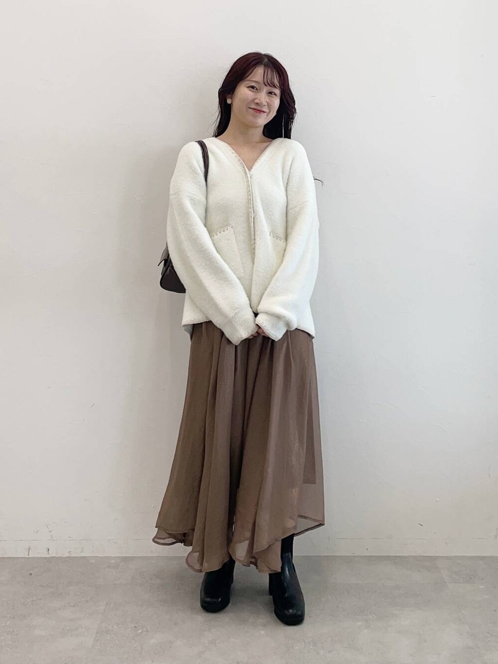 ブラック系のブーツ、ブラウン系のハンドバッグ、ホワイト系のブルゾンを着用したレディースの秋コーディネートの4枚目の写真