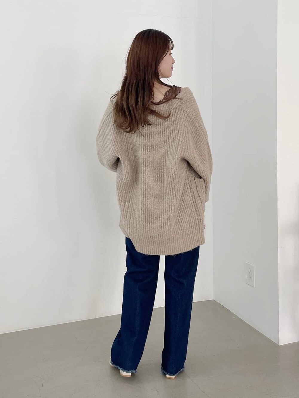 ブルー系のデニムパンツ、ホワイト系のボストンバッグ、ホワイト系のパンプスを着用したレディースの秋コーディネートの2枚目の写真