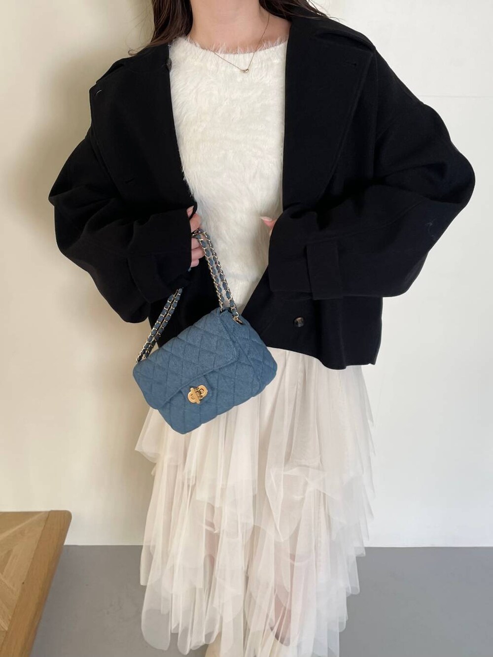 ブラック系のその他アウター、ホワイト系のブーツ、ホワイト系のスカートを着用したレディースの冬コーディネートの3枚目の写真