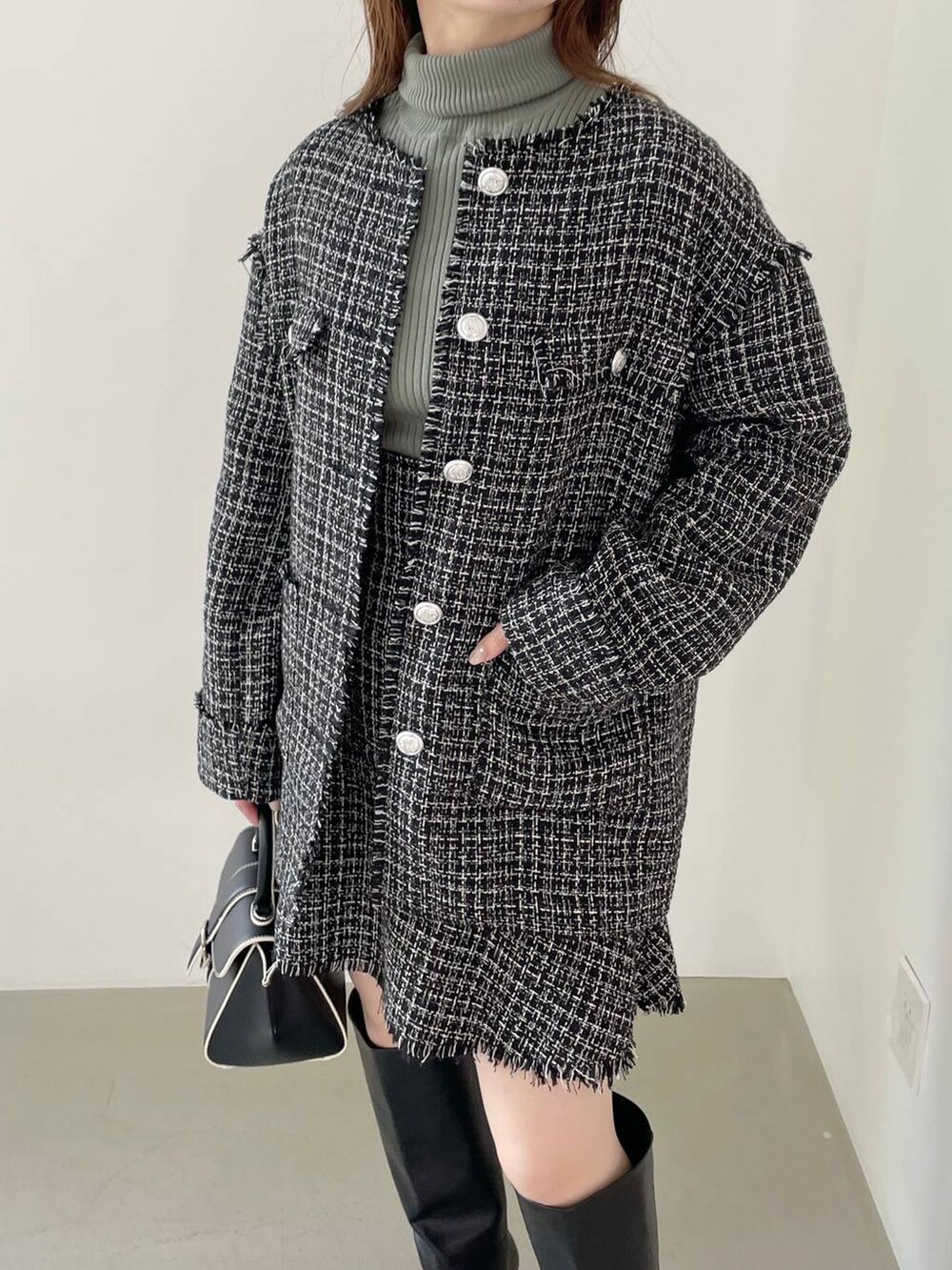 ブラック系のハンドバッグ、ブラック系のブーツ、ブラック系のノーカラージャケットを着用したレディースの秋コーディネートの3枚目の写真