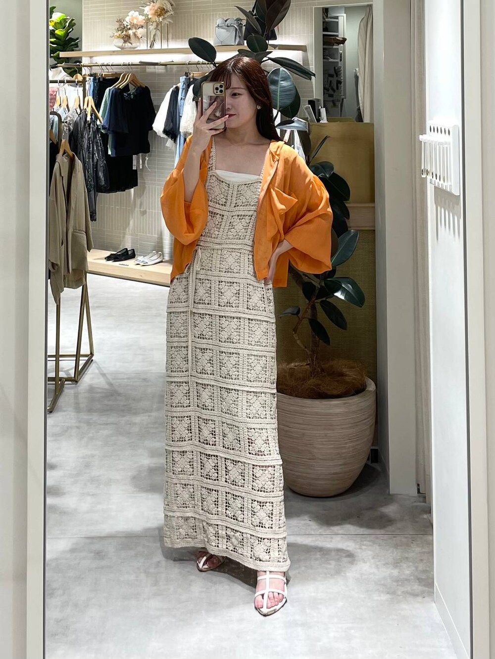 ホワイト系のワンピース、オレンジ系のパーカー、ホワイト系のサンダルを着用したレディースの夏コーディネートの4枚目の写真