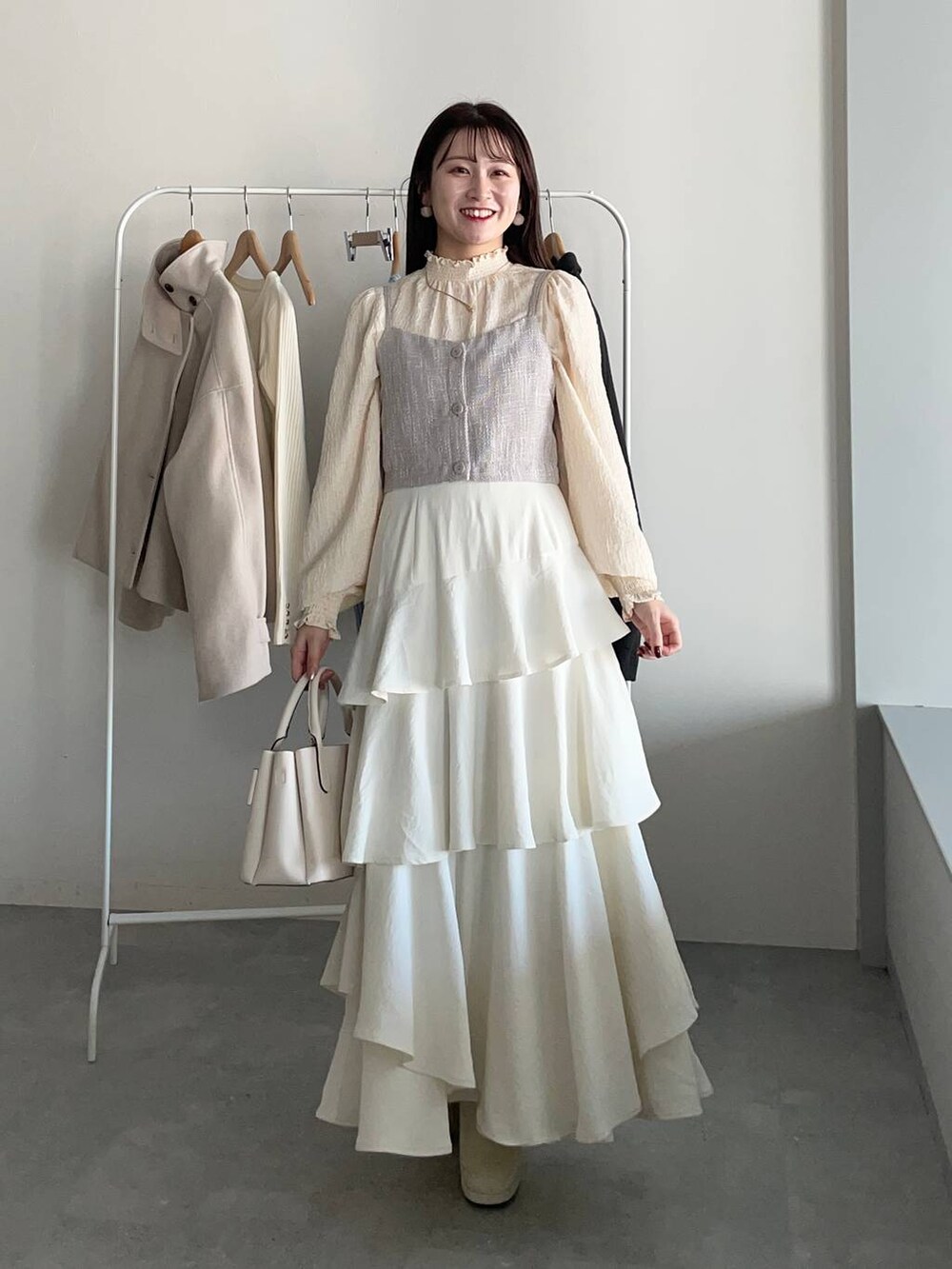 ホワイト系のピーコート、ホワイト系のブーツ、ホワイト系のスカートを着用したレディースの冬コーディネートの3枚目の写真