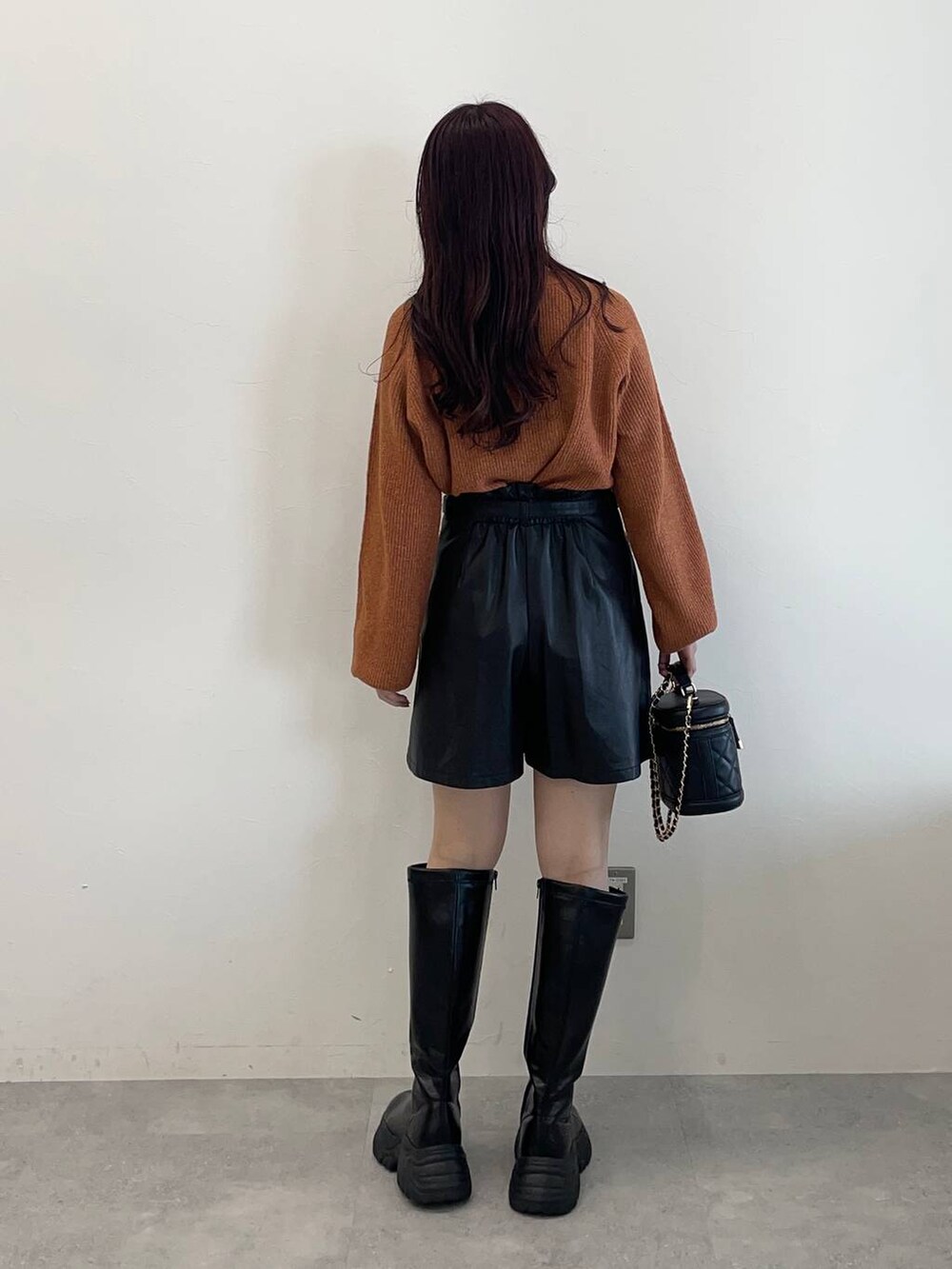 ブラック系のブーツ、ブラック系のその他パンツ、オレンジ系のニット/セーターを着用したレディースの秋コーディネートの5枚目の写真