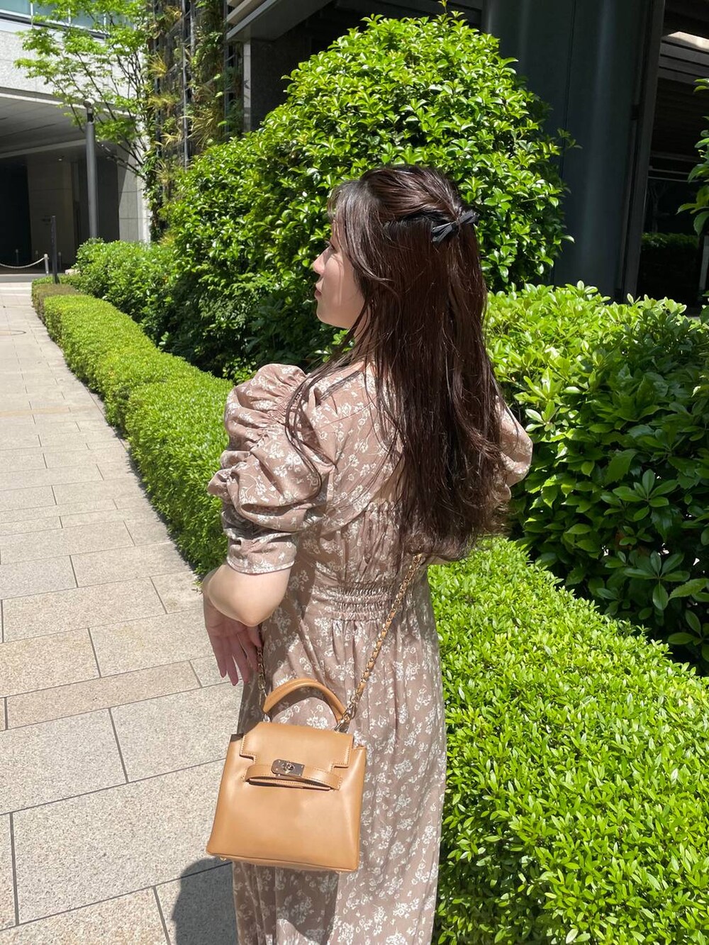 ブラウン系のショルダーバッグ、ベージュ系のワンピースを着用したレディースの春コーディネートの4枚目の写真