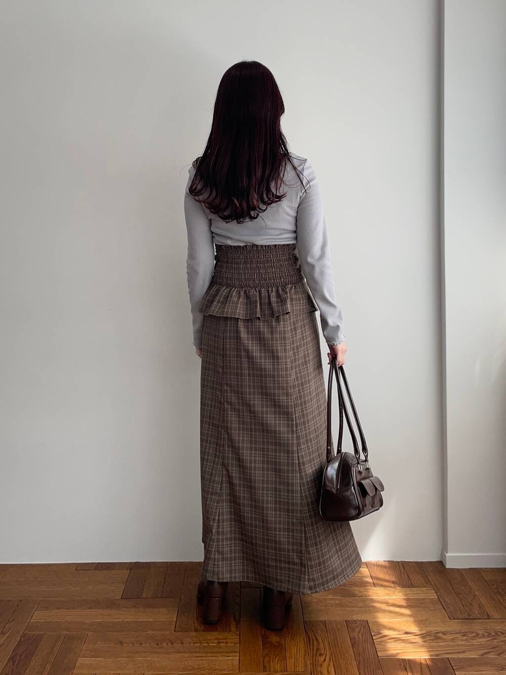 ブラウン系のブーツ、ブラウン系のスカート、グレー系のTシャツ/カットソーを着用したレディースの秋コーディネートの2枚目の写真