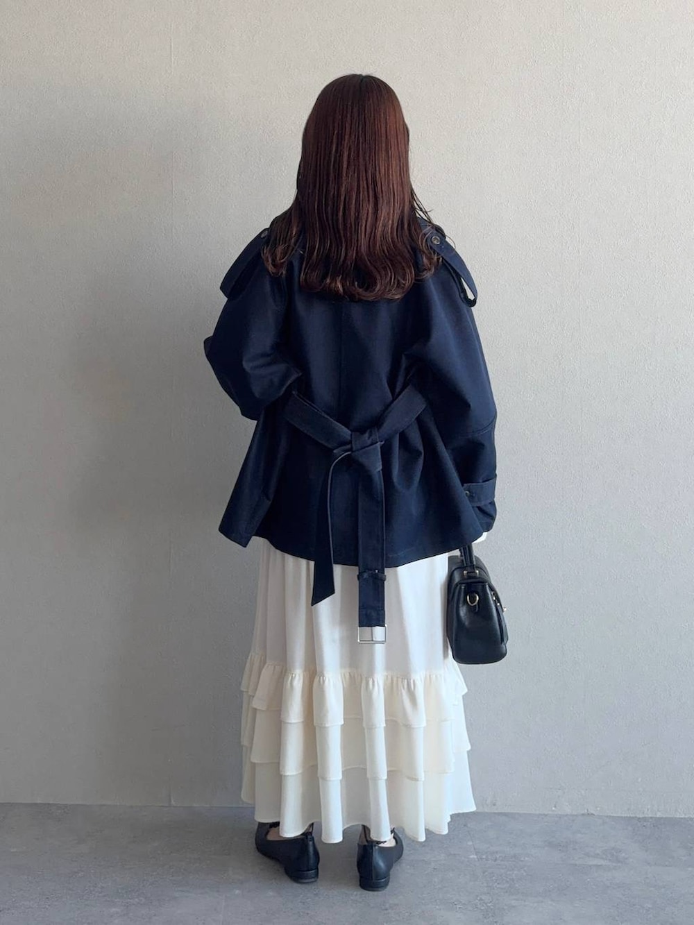 ブラック系のショルダーバッグ、ブラック系のパンプス、ホワイト系のワンピースを着用したレディースの冬コーディネートの2枚目の写真