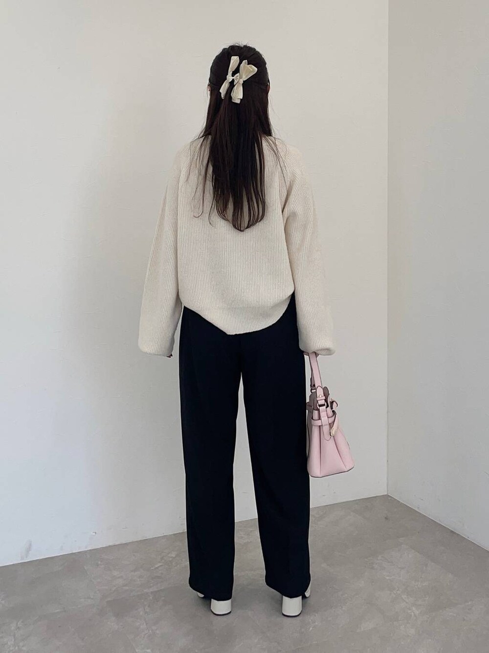 ピンク系のショルダーバッグ、ホワイト系のブーツ、ホワイト系のニット/セーターを着用したレディースの冬コーディネートの2枚目の写真