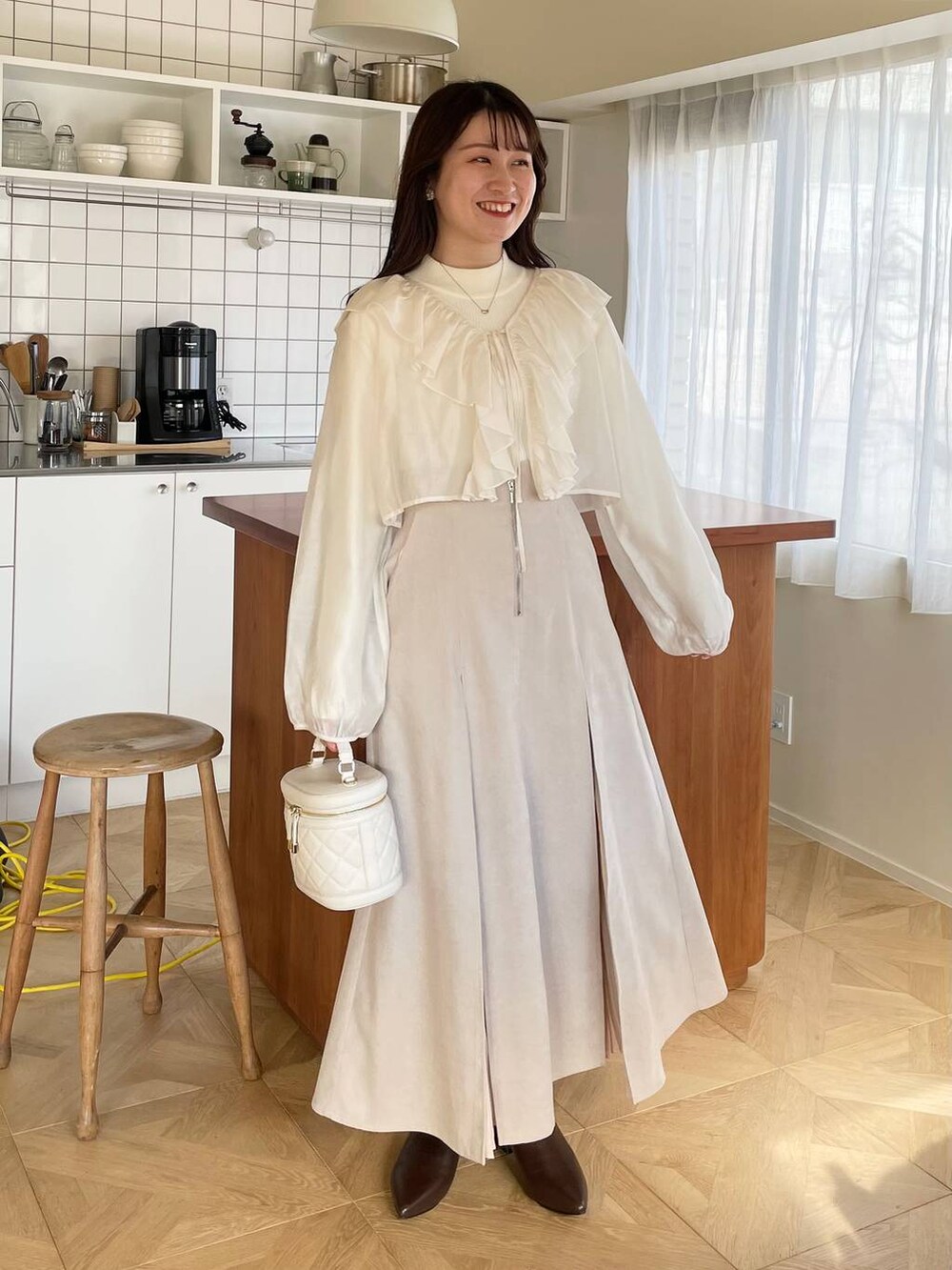 ホワイト系のショルダーバッグ、ブラウン系のブーツ、ベージュ系のブルゾンを着用したレディースの冬コーディネートの5枚目の写真