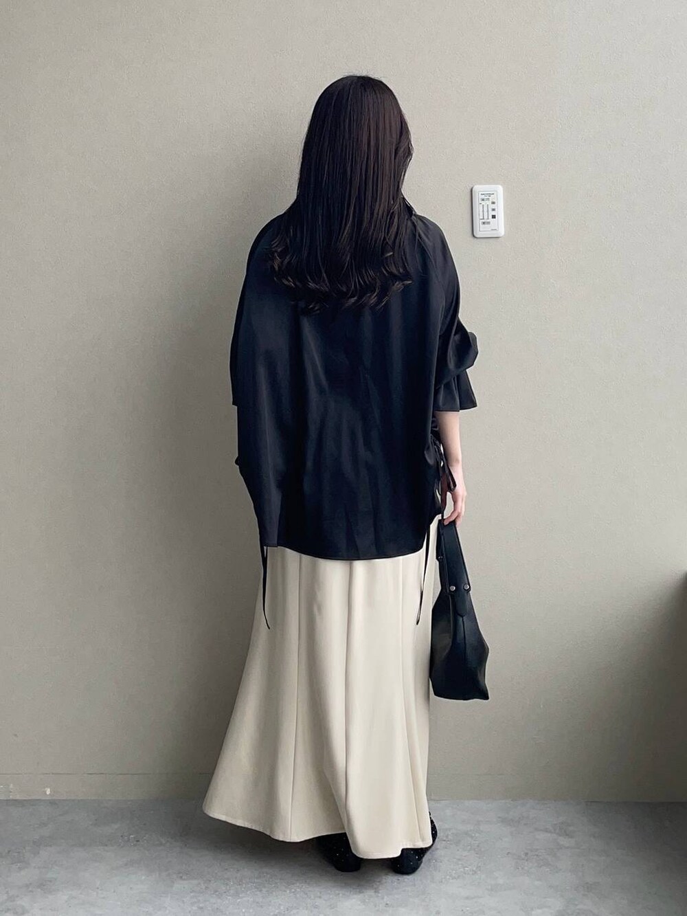 ベージュ系のスカート、ブラック系のバレエシューズ、ブラック系のショルダーバッグを着用したレディースの春コーディネートの2枚目の写真