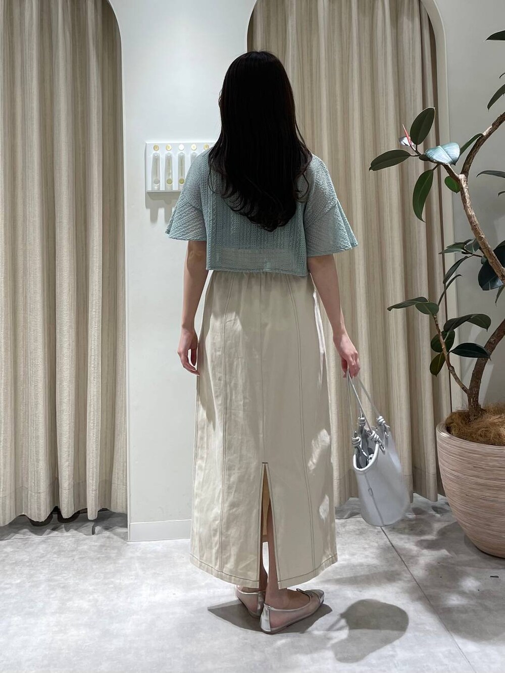 シルバー系のバレエシューズ、グリーン系のカーディガン/ボレロ、ホワイト系のスカートを着用したレディースの春コーディネートの2枚目の写真