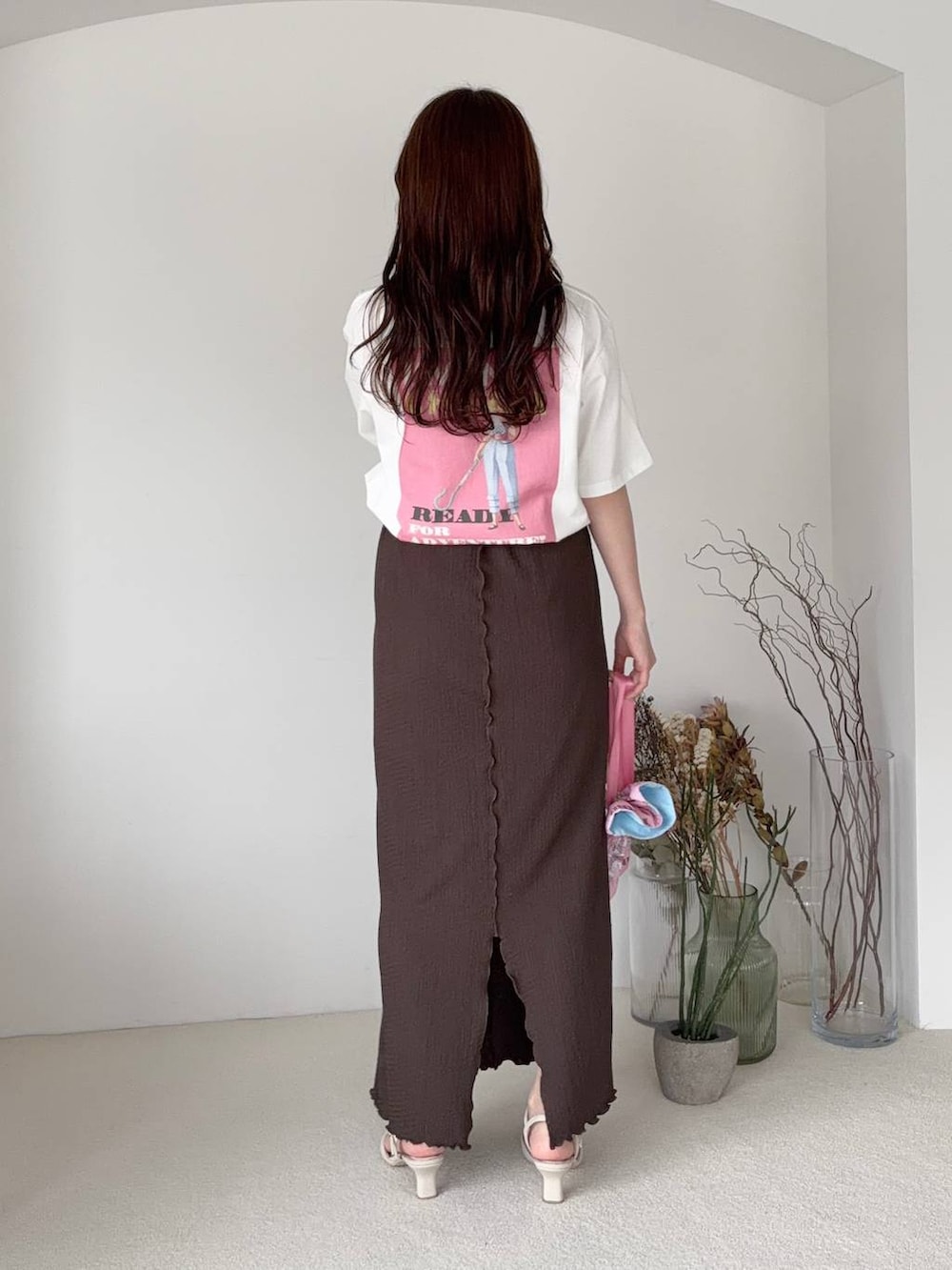 ブラウン系のスカート、ホワイト系のTシャツ/カットソー、ホワイト系のサンダルを着用したレディースの夏コーディネートの2枚目の写真