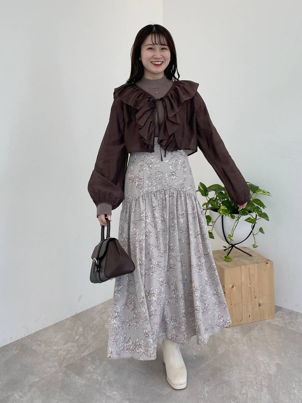 ブラウン系のハンドバッグ、ホワイト系のブーツ、ブラウン系のシャツ/ブラウスを着用したレディースの冬コーディネートの2枚目の写真