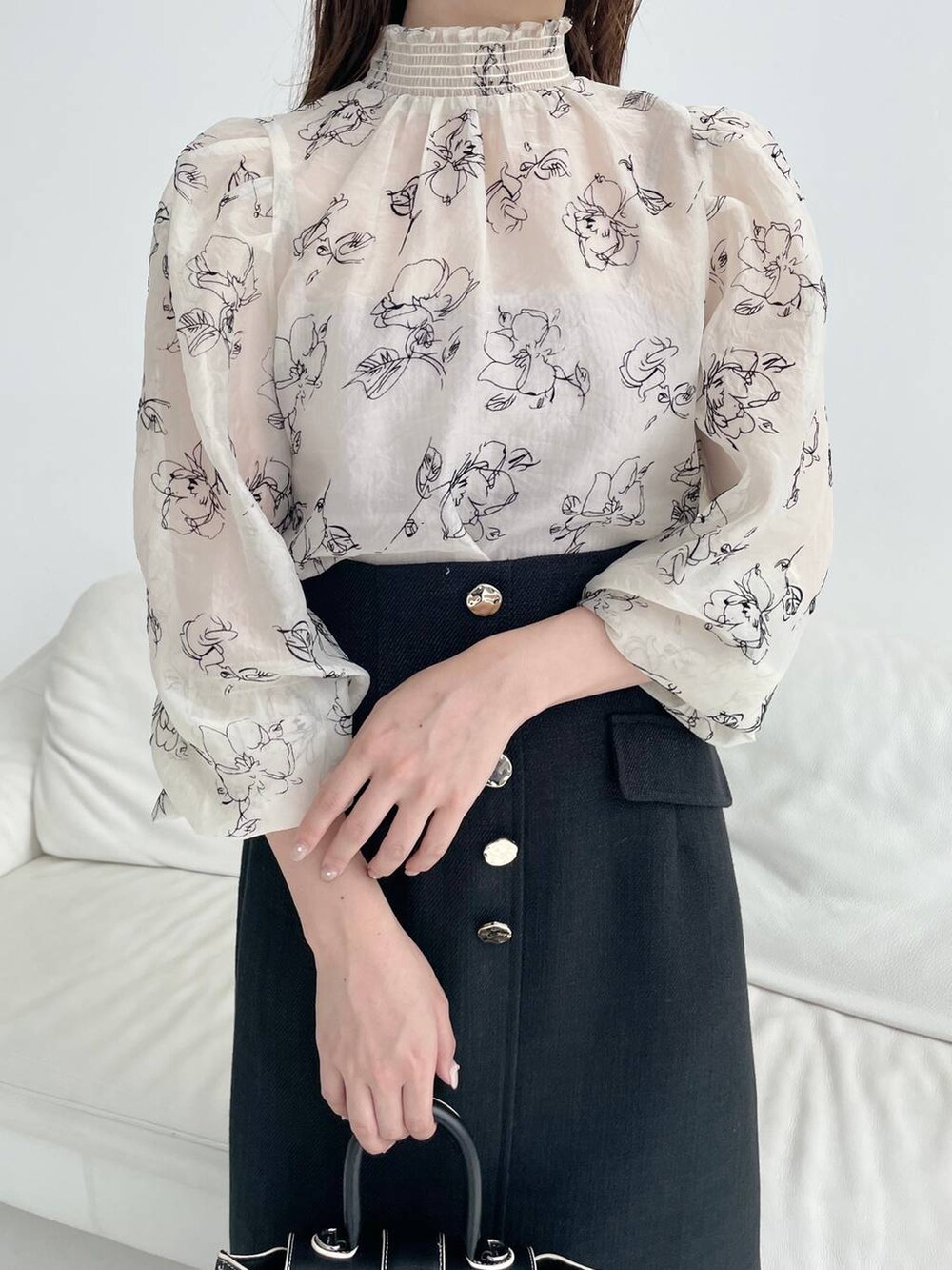 ブラック系のハンドバッグ、ホワイト系のパンプス、ブラック系のスカートを着用したレディースの秋コーディネートの3枚目の写真