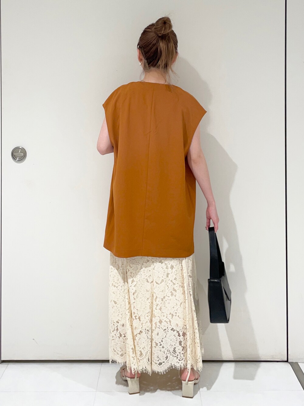 ブラック系のタンクトップ、ホワイト系のスカート、オレンジ系のベストを着用したレディースの夏コーディネートの2枚目の写真