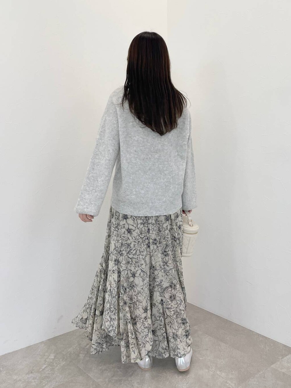 グレー系のニット/セーター、ベージュ系のスカート、ホワイト系のショルダーバッグを着用したレディースの冬コーディネートの5枚目の写真