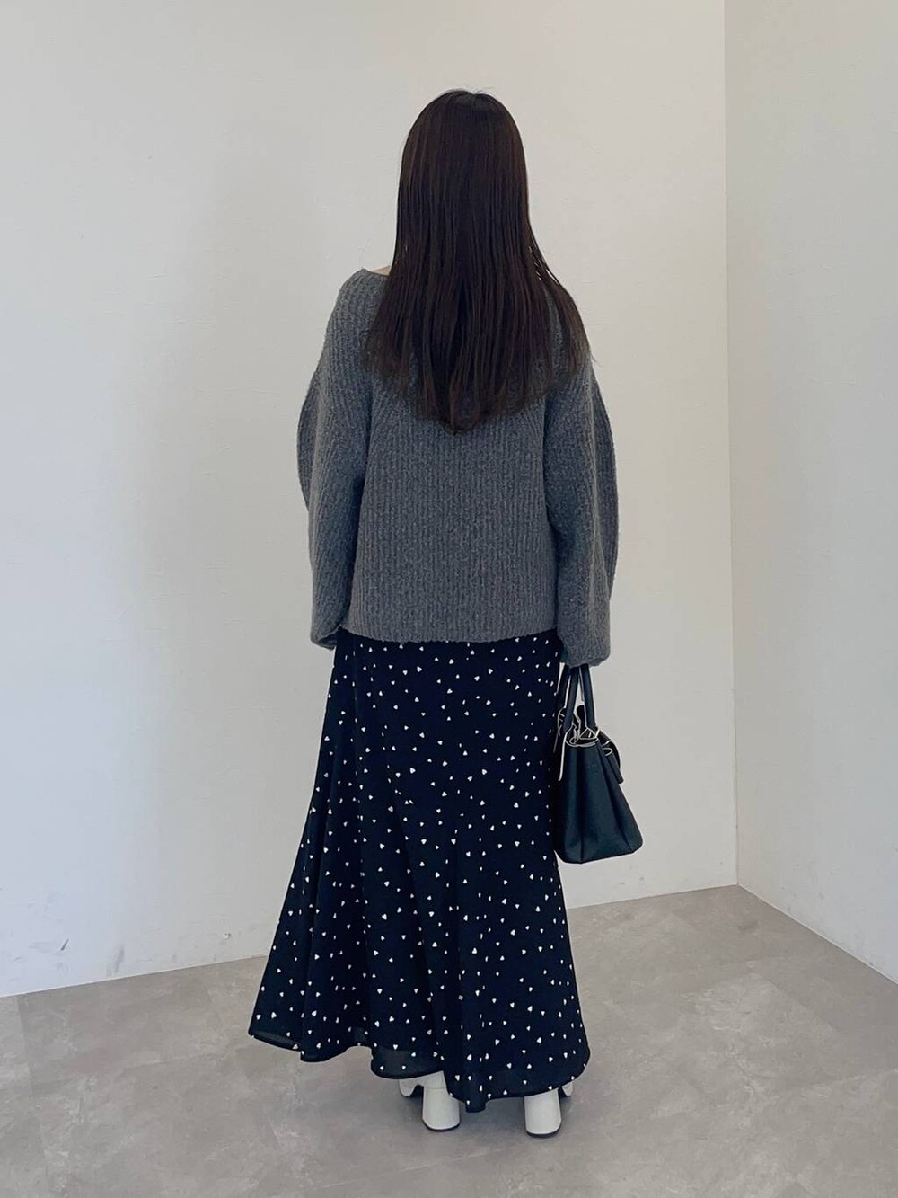 ホワイト系のブーツ、グレー系のニット/セーター、ブラック系のショルダーバッグを着用したレディースの冬コーディネートの2枚目の写真